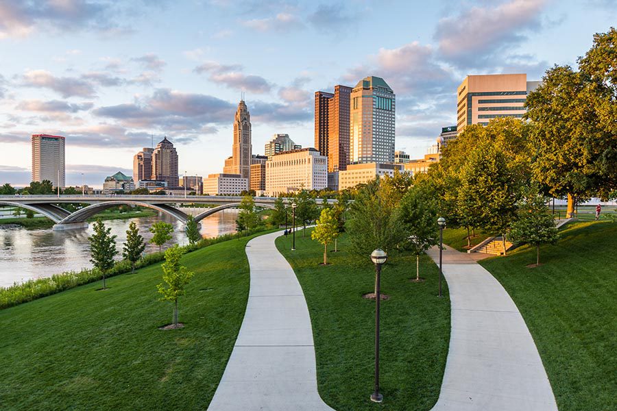 Columbus, OH Insurance - Paved Walking Paths in Columbus, Ohio, Surrounded by Green Grass, the River and Skyline Turning Orange in the Sunset