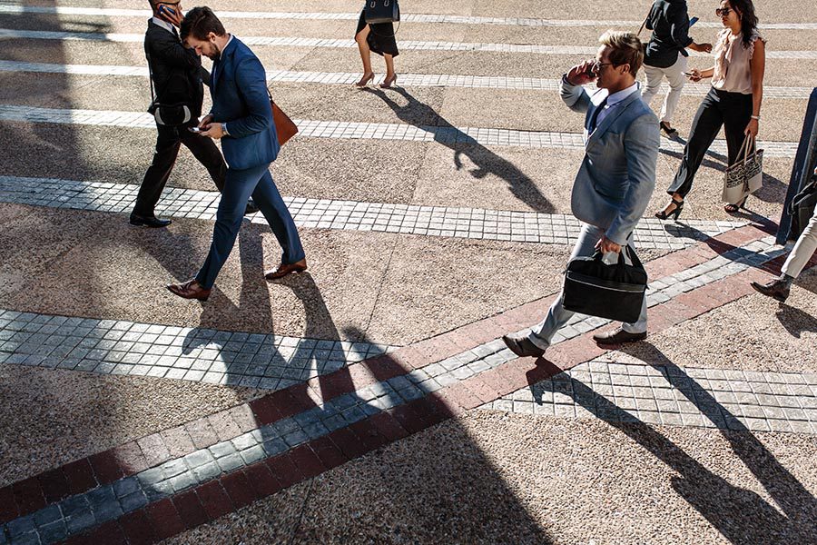 Contact - Busy People Cross a City Street, Dressed for Work, One Man Carrying a Briefcase and Using a Cell Phone
